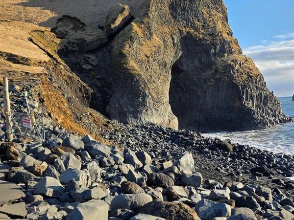 Where a sandy beach once extended outward, there is now deep water and a shoreline strewn with large boulders. The sea now flows into the cave that was previously accessible on foot. Coastal erosion now reaches almost all the way up to the warning sign on the ridge.