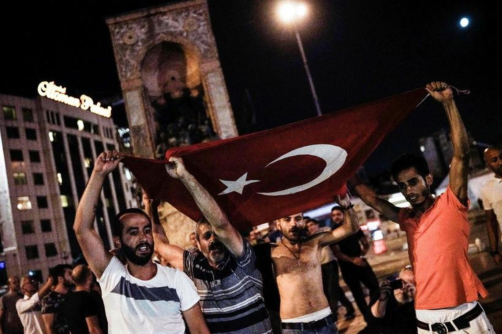 Nokkrir menn halda á tyrkneska fánanum á Taksim-torgi í Istanbúl.