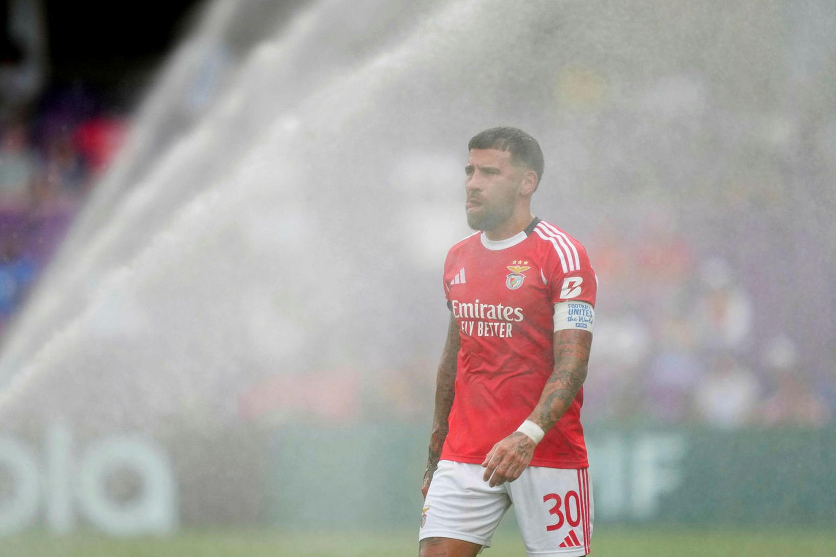 Nicolas Otamendi kælir sig í vökvunarkerfi vallarins á dögunum.