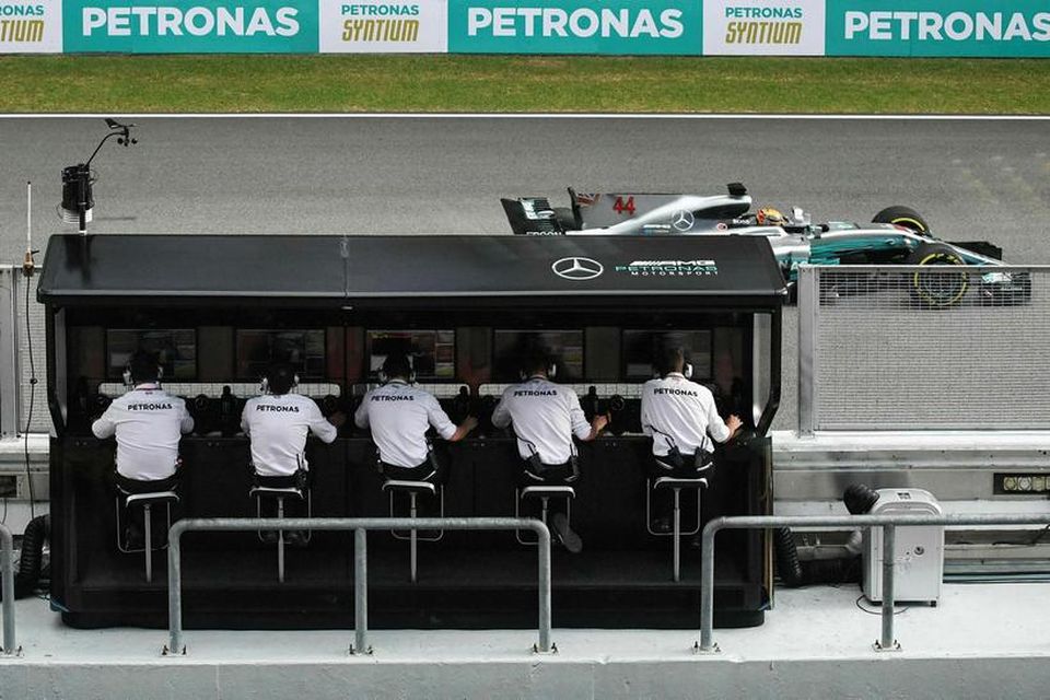 Lewis Hamilton í tímatökunni í Sepang og tæknimenn Mercedes fylgjast með starfsemi bílsins á stjórnborðinu …