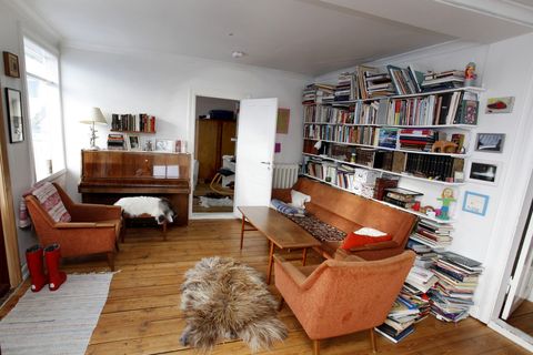 The living room features plenty of books, warm hued furniture and animal skins.