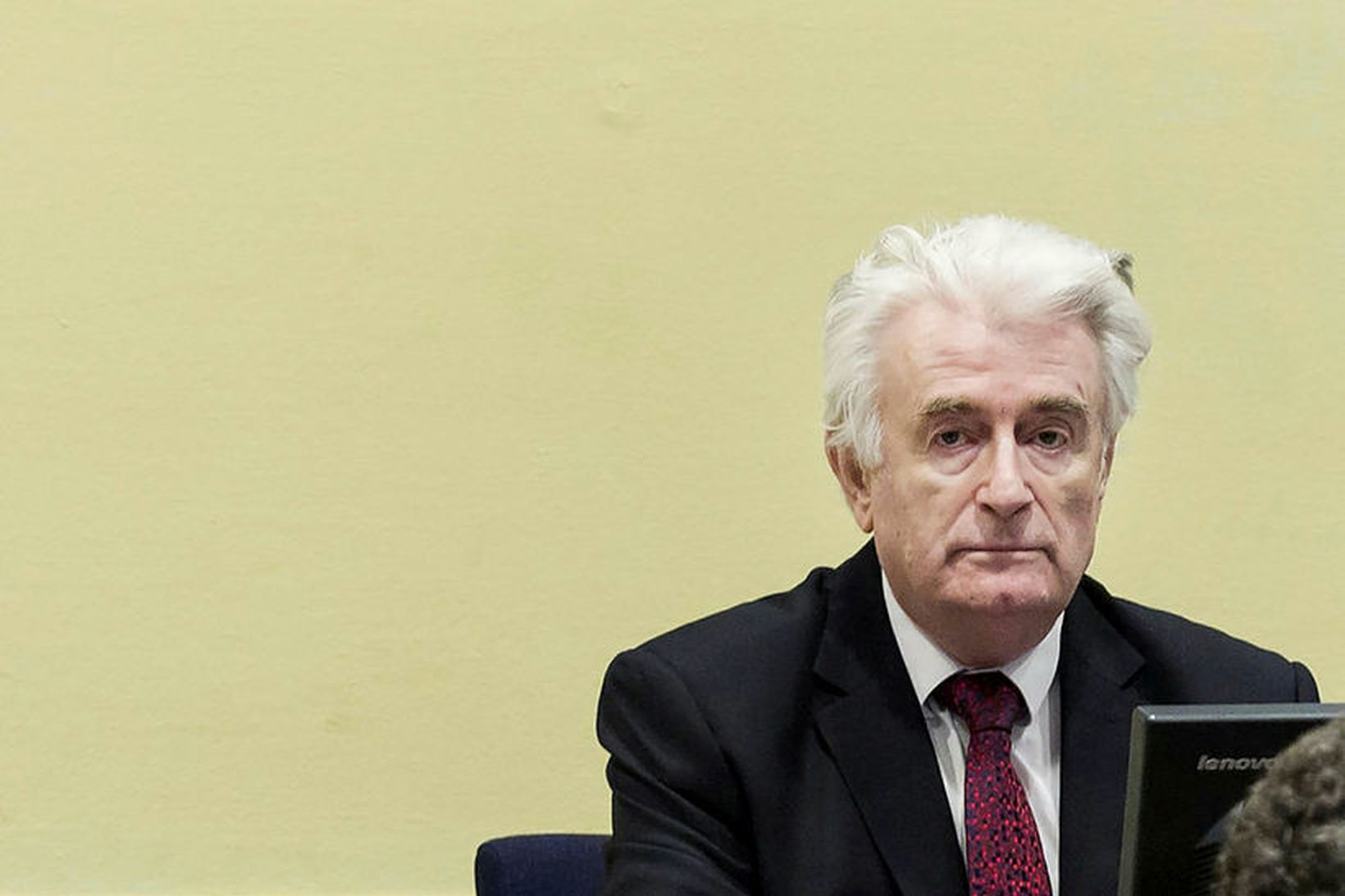 Radovan Kara­džić situr í réttarsalnum í Haag í dag.