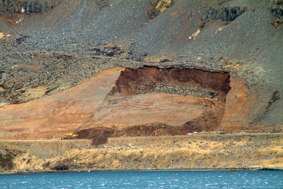 Eins og sést er skriðan efnismikil en hún lokaði veginum. Grafan sem Bjarni stýrði sést …