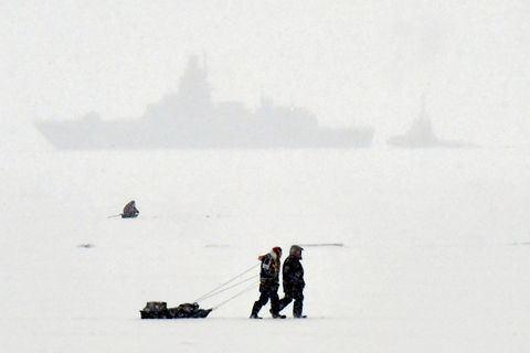 Veiðimenn ganga yfir ísilagðan Kirjálabotn við Sankti Pétursborg. Í bakgrunni hvílir herskip. Mynd frá desember …