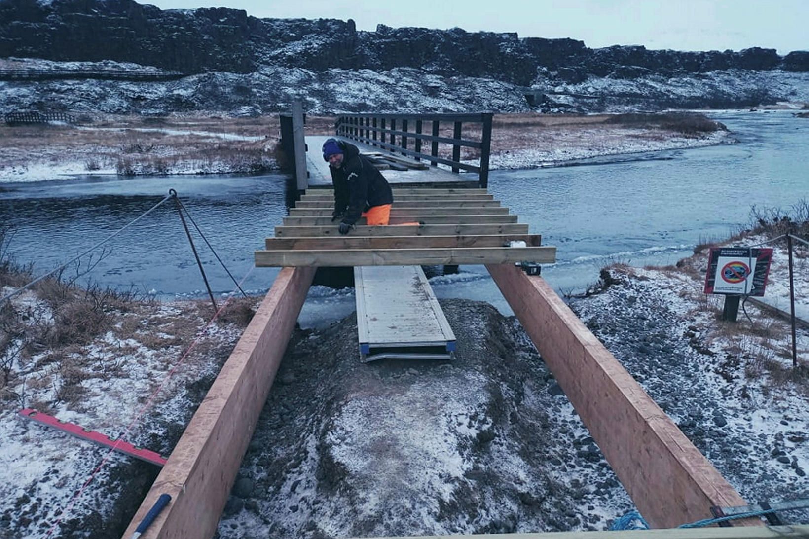 Friðrik Einarsson vinnur að viðgerð á göngubrúnni yfir miðálinn.