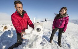 Bjarni Björnsson and Hanna Reynolds wipe snow off the lens of a webcam pointed at …