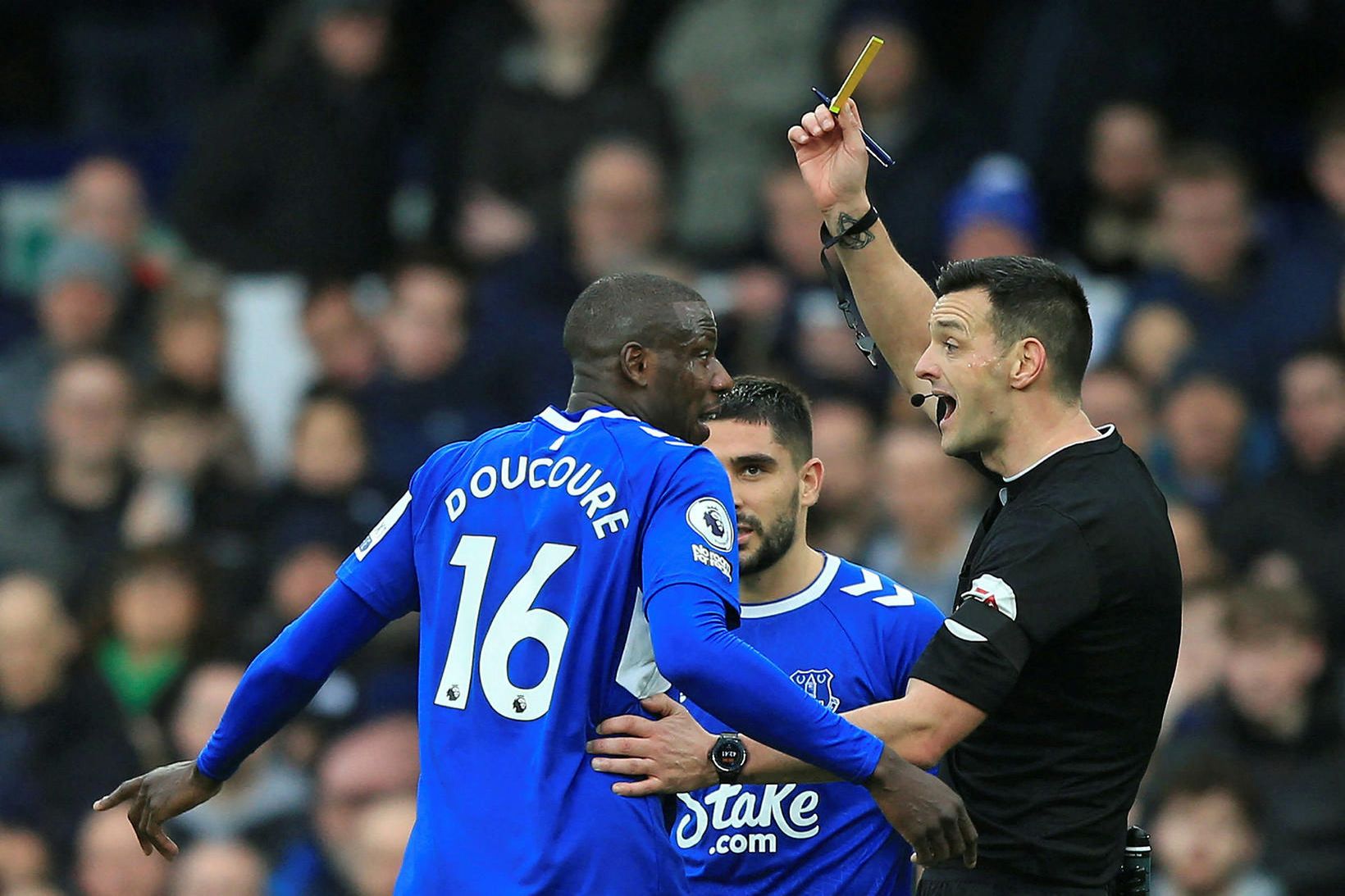 Andrew Madley sýnir Abdoulaye Doucoure miðjumanni Everton gula spjaldið eftir …