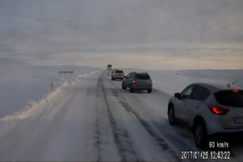 Cars stopped along a snowy, icy highway.