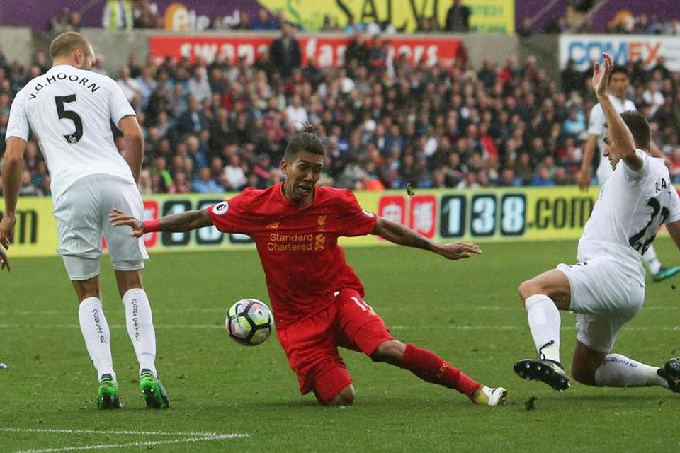 Roberto Firmino, leikmaður Liverpool, fellur í vítateig Swansea City eftir viðskipti sín við Angel Rangel, …