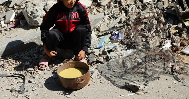 Palestínskur drengur í Al-Shati-flóttamannabúðunum á Gasasvæðinu í dag með súpu í potti sem hann fékk …