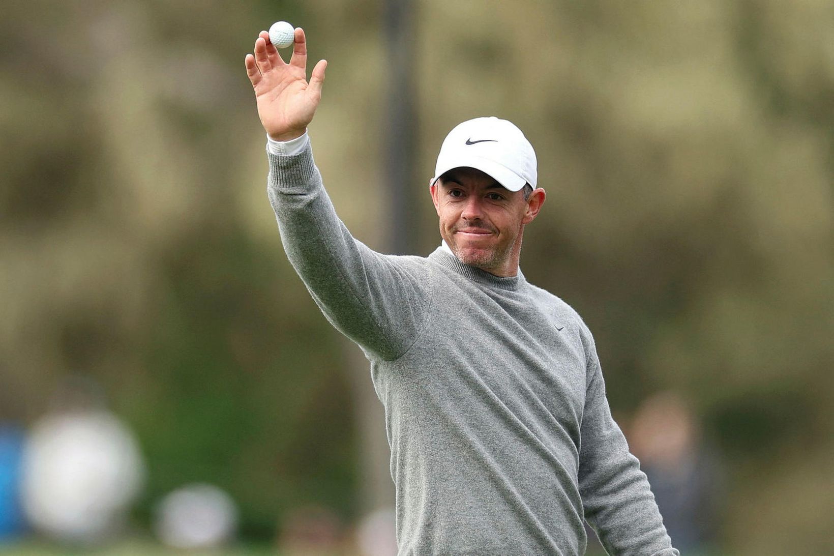 Rory McIlroy veifar til áhorfenda eftir að hann fór holu …