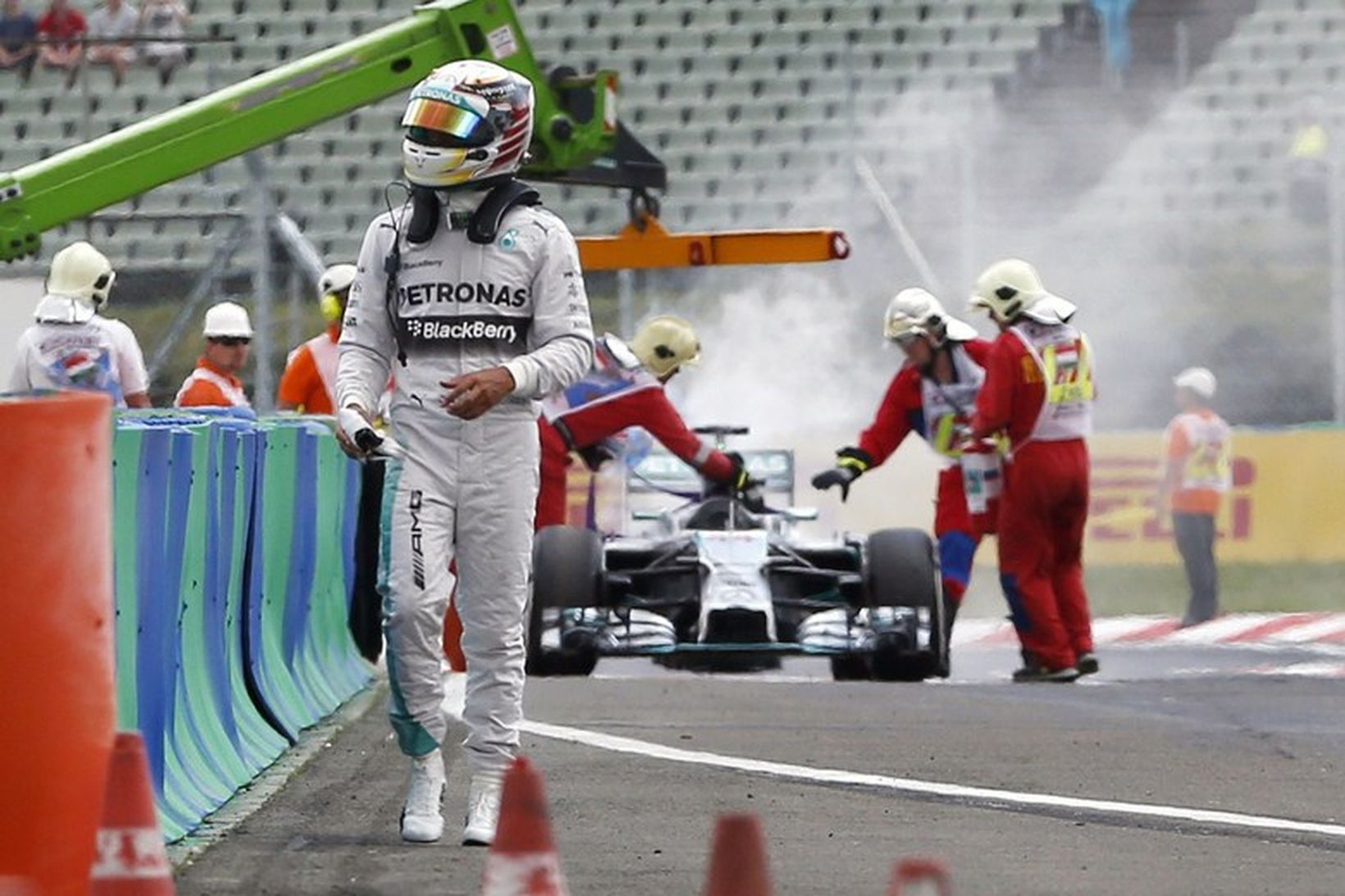 Svekktur gengur Lewis Hamilton frá biluðum og brennandi bíl sínum …