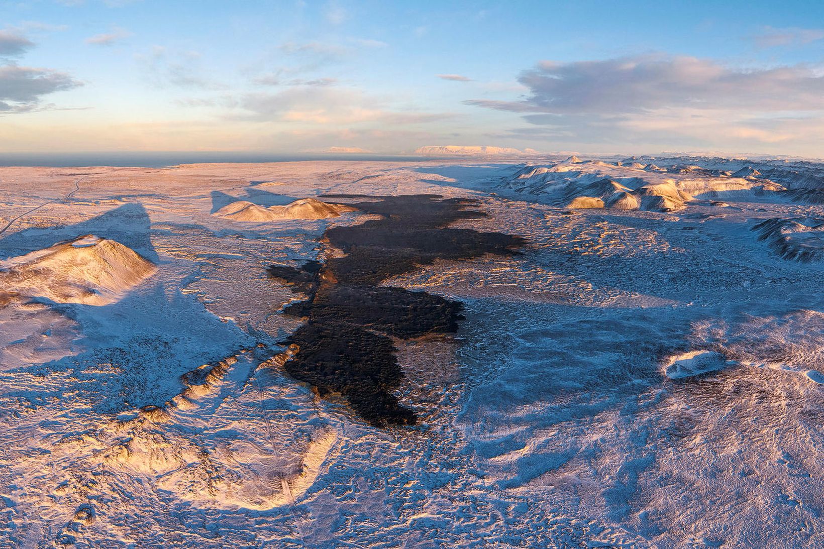 Horft til norðurs með Sundhnúkagígaröðinni og yfir svart hraunið sem …