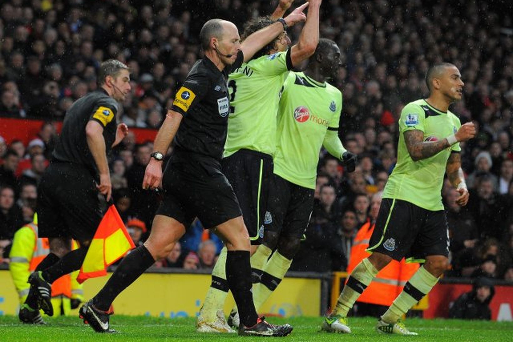 Mike Dean bendir á miðjupunktinn og leikmenn Newcastle fagna.