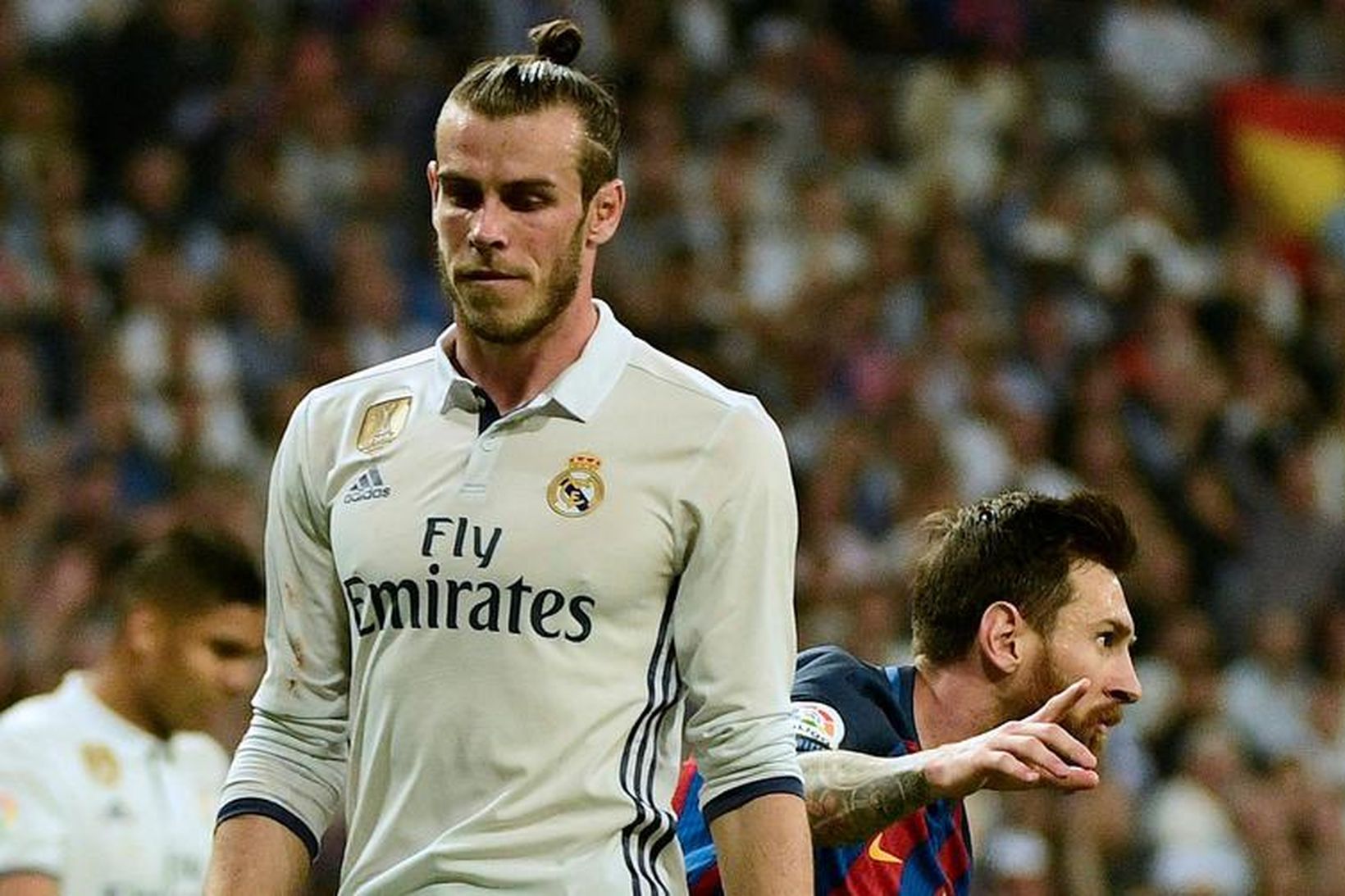 Gareth Bale er niðurlútur en Lionel Messi fagnar í bakgrunni.