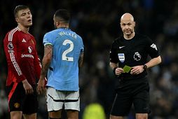 Anthony Taylor með gula spjaldið í höndunum á meðan Rasmuns Höjlund og Kyle Walker ræða …