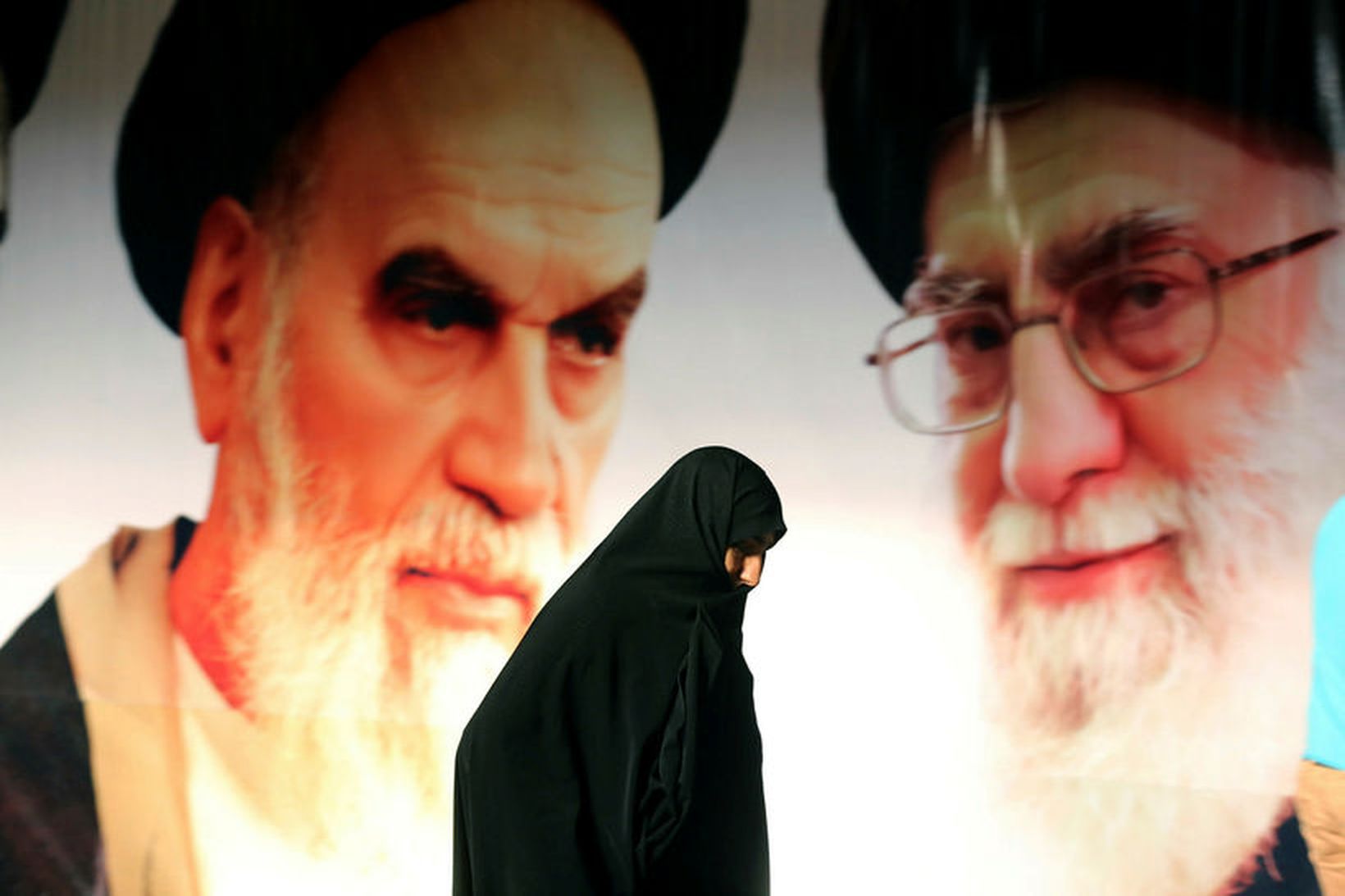Kona gengur fram hjá risavöxnu veggspjaldi af Ayatollah Ali Khamenei, …