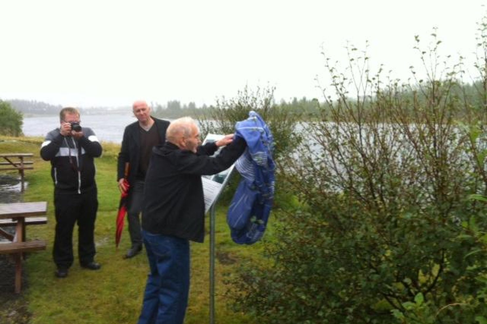 Ágúst Sæmundsson afhjúpar skiltið sem stendur þar sem brúin stóð …