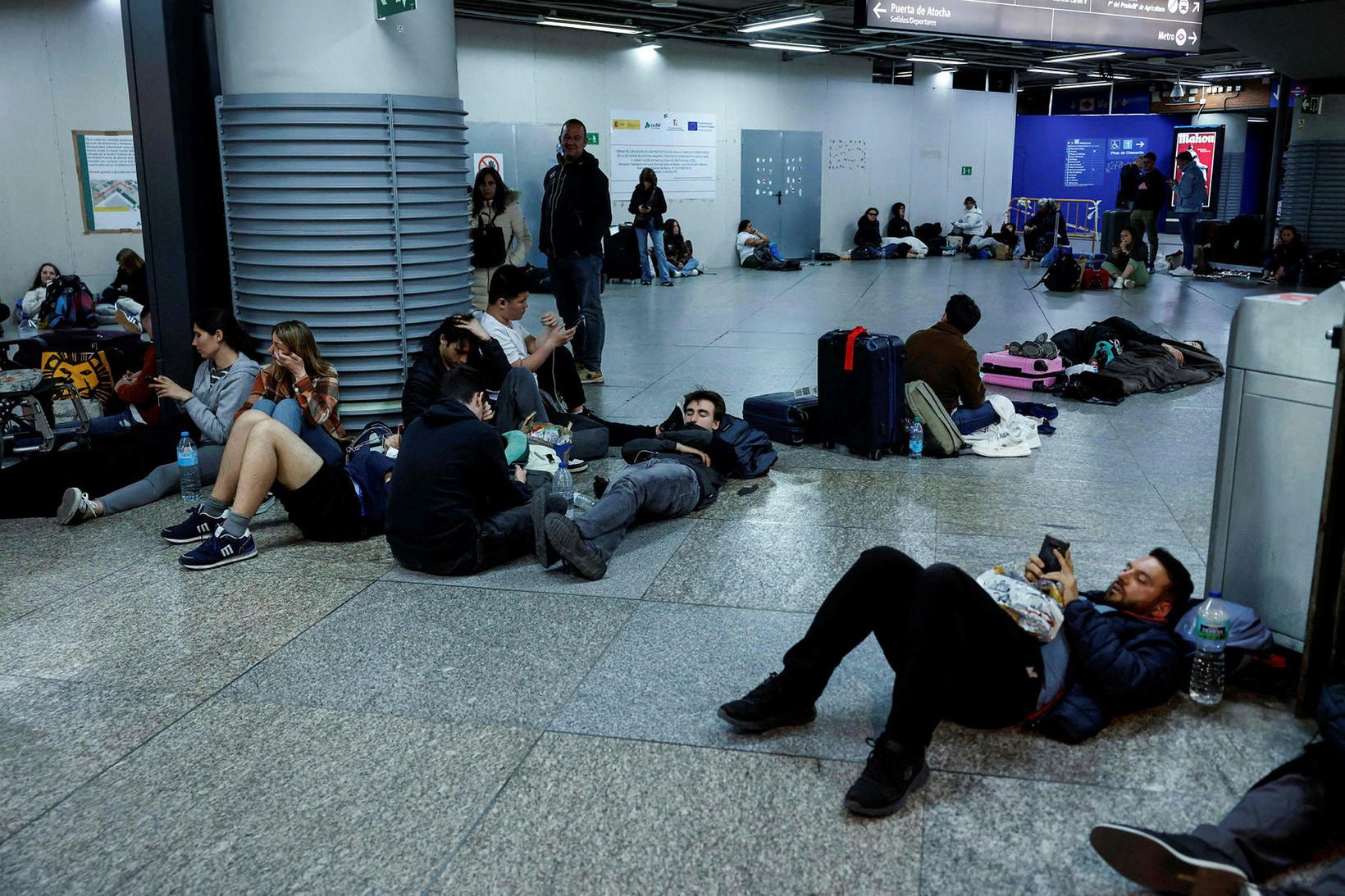 Ferðamenn liggja á gólfinu á Atocha-lestarstöðinni í Madrid á Spáni.