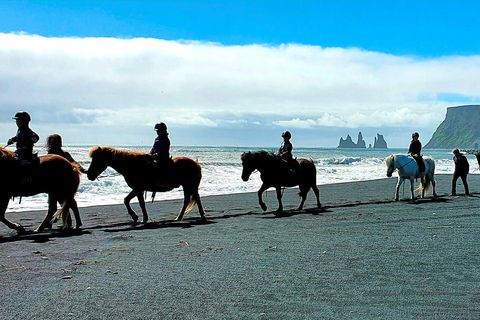 Young riders on the beach. Reynisdrangar sea stacks in the background.