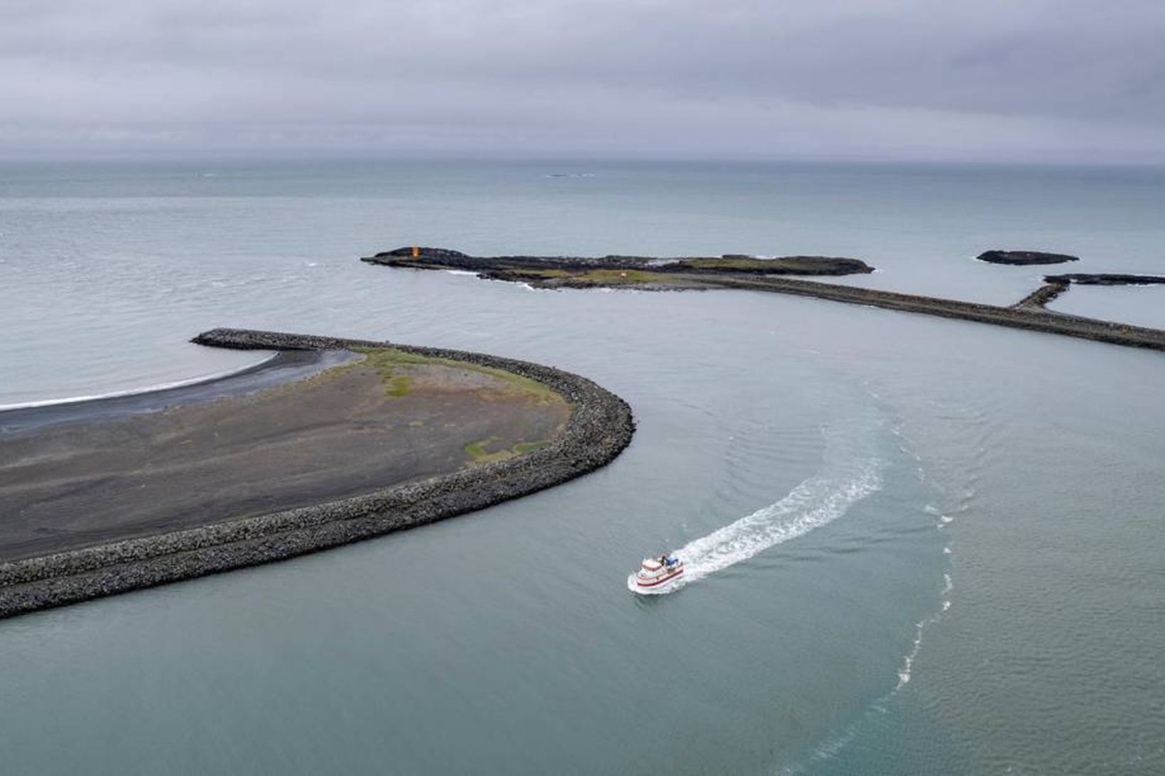 Bátur siglir inn Hornafjarðarós. Grynnslin eru fyrir framan.