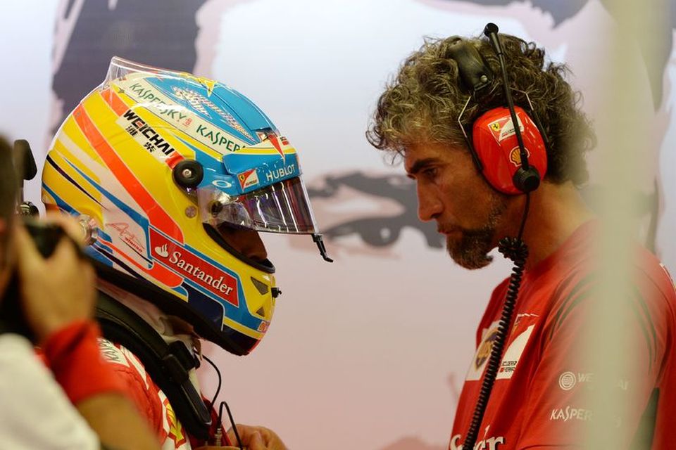 Fernando Alonso fær aðstoð tæknimanns hjá Ferrari við að skrýðast fyrir akstur í Singapúr í …