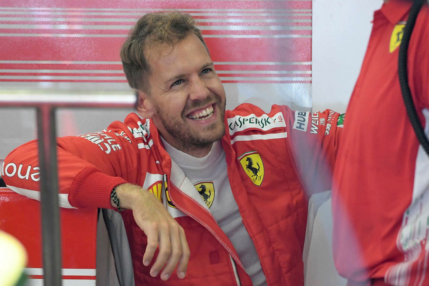 Sebastian Vettel slær á létta strengi við vélvirkja í bílskúr …