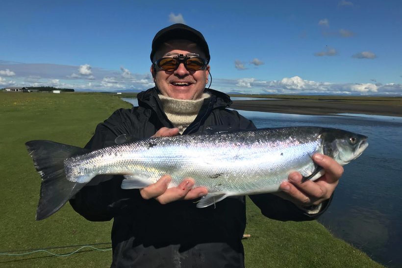 Færeyskur veiðimaður með silfraðan lax af Austurbakka Hólsár. Þar er …