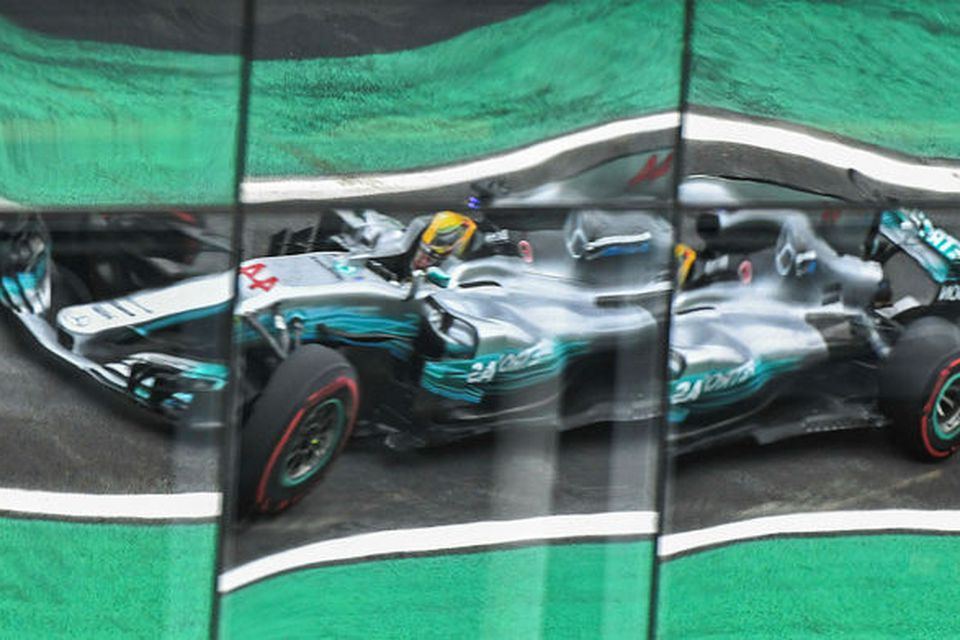Bíll Lewis Hamilton speglast í gluggum stúku í Interlagos.