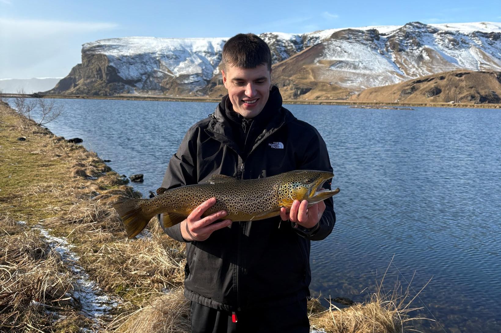 Jakub Szweda með urriða sem hann veiddi á svarta straumflugu …