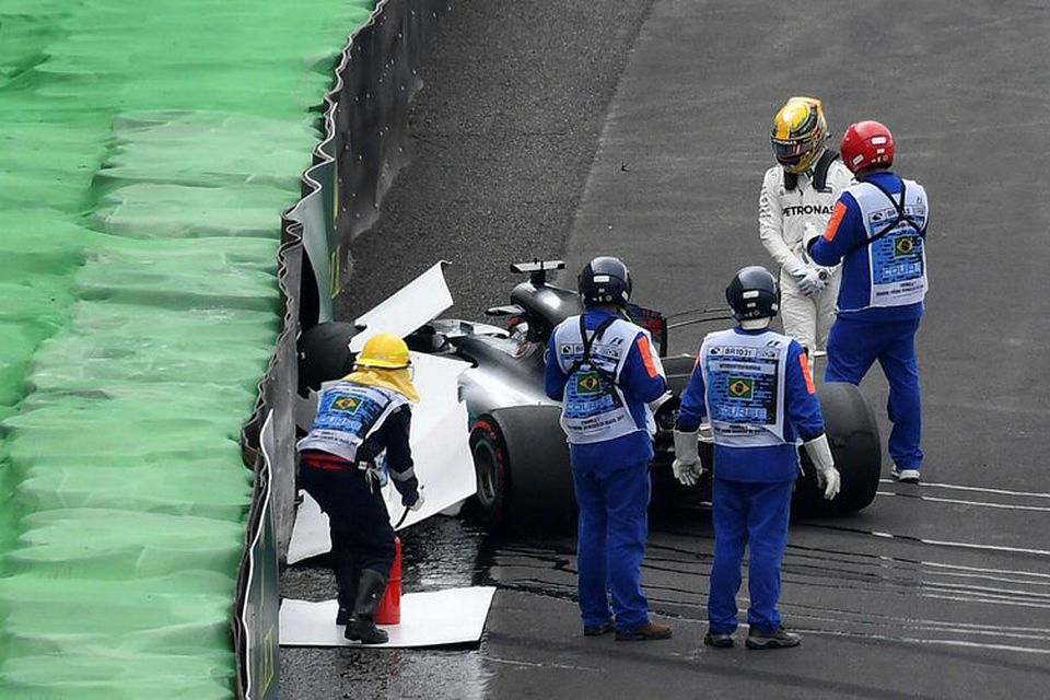 Lewis Hamilton skoðar bíl sinn eftir skellinn við öryggisveggnum í Sao Paulo.