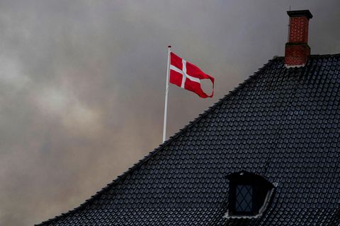 Danski fáninn blaktir við hún við danska fjármálaráðuneytið, þriðjudaginn 16. apríl, í reykjarmekki frá Børsen-eldsvoðanum.