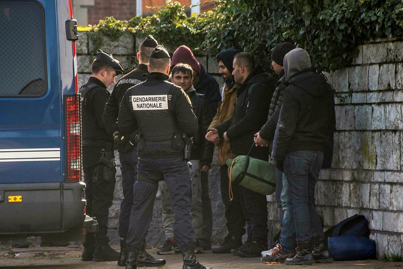 Franskir lögreglumenn skoða skilríki flóttamanna í Calais.