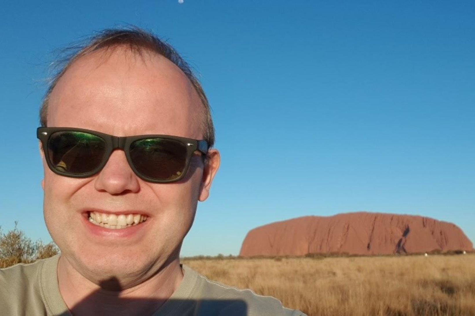 Ferðalangurinn með klettinn Uluru í bakgrunni.