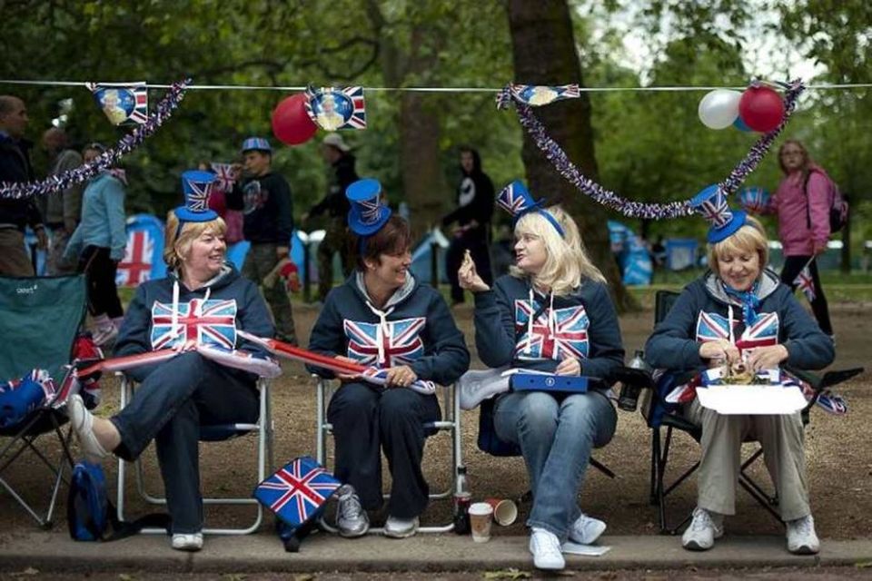 Stuðningsmenn bresku konungsfjölskyldunnar sitja fyrir utan Buckinghamhöll í London og bíða eftir því að tónleikar …