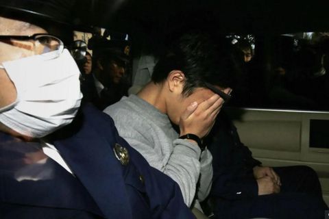Takahiro Shiraishi hylur andlit sitt í höndum sér eftir handtökuna og sést hér í aftursæti …