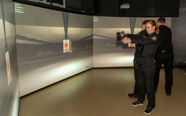 Lögreglunemar munda lasertengdar Glock-skammbyssur í hermi menntasetursins.
