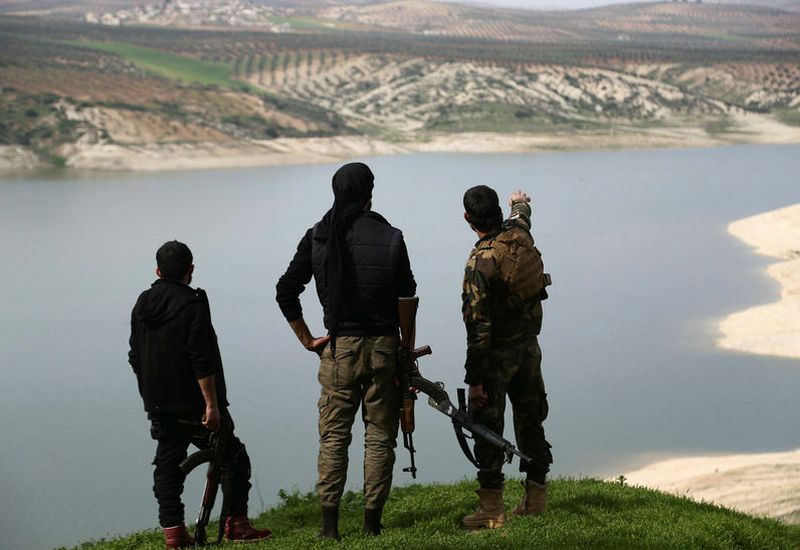 . Members of the armed Kurdish forces looking at lake Maydanki in Afrin, Syria.