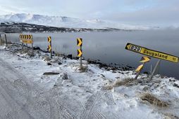 Bifreiðin hafnaði á skiltinu og endaði úti í sjó.