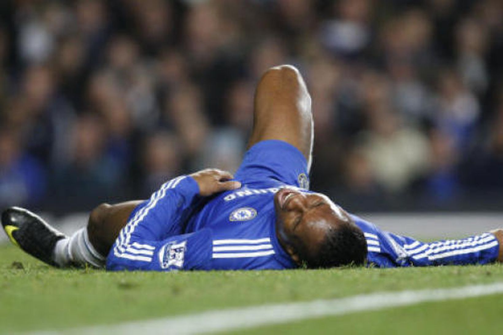 Didier Drogba liggur óvígur í grasinu á Stamford Bridge í …