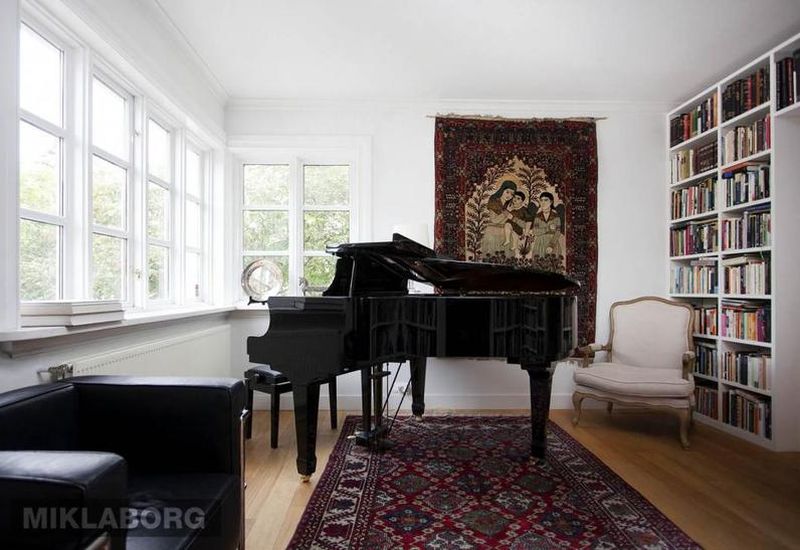 The living room features wall-to-wall books and a grand piano.