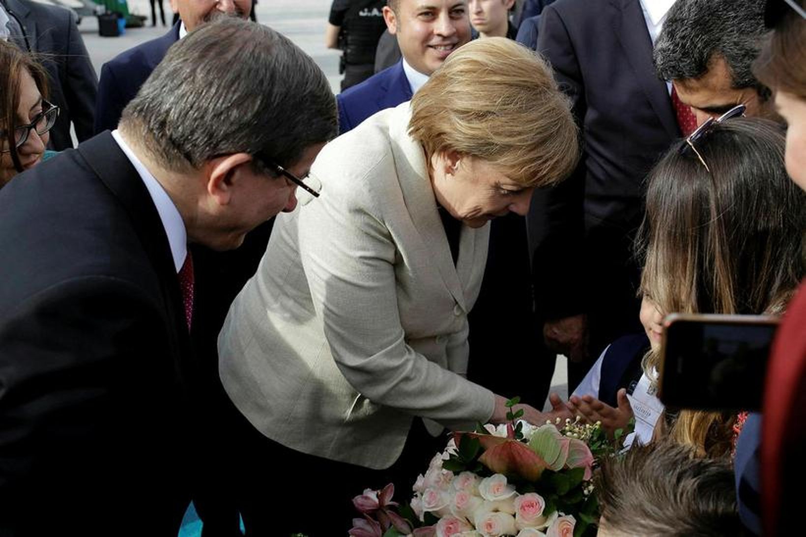 Angela Merkel tekur við blómum frá börnum á flugvellinum í …