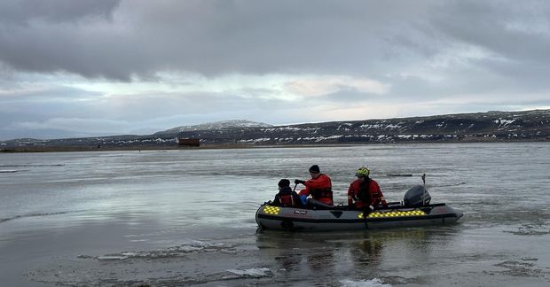 Björgunarsveitarmenn sigla yfir tún til að koma erlendum ferðamanni til bjargar.